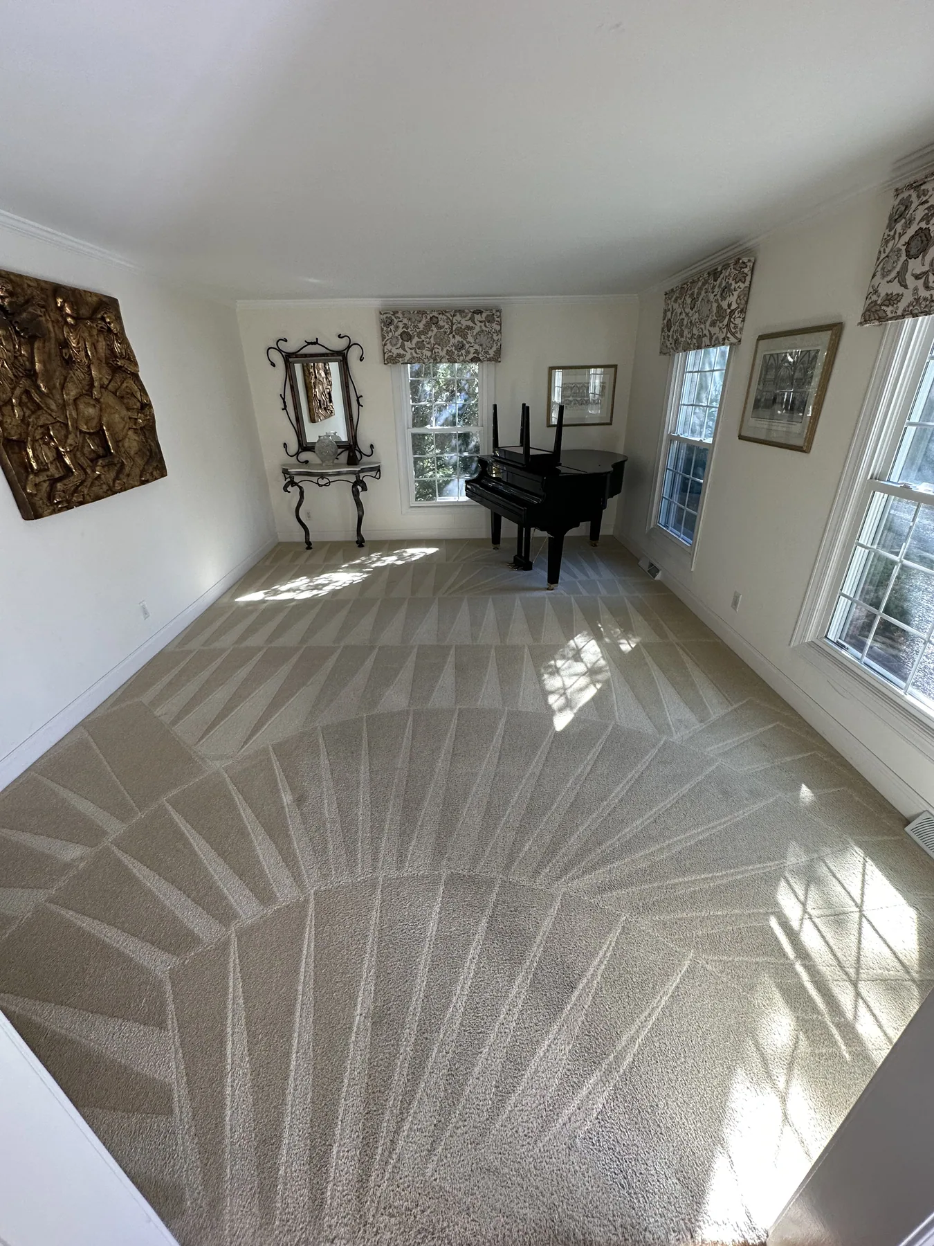 Fan-pattern vacuum lines left in a freshly dry-cleaned carpet in a sunlit living room with a piano
