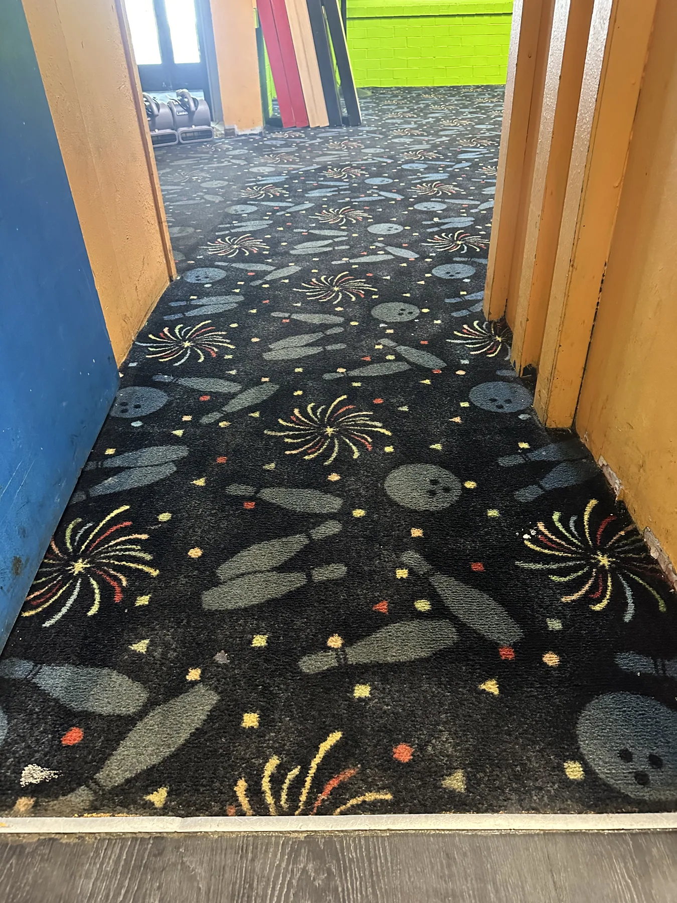 Same bowling and firework-patterned hallway carpet restored to full color after dry cleaning, same doorway and threshold as the before shot