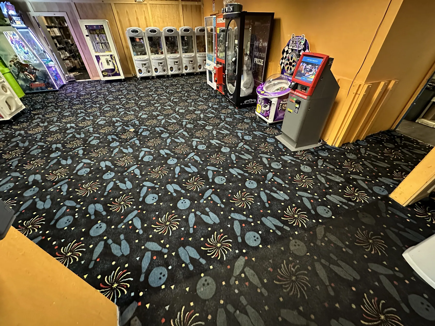 Patterned commercial carpet in an arcade and family entertainment center after cleaning, arcade games in background